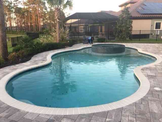 A round, wavy pool with a jacuzzi